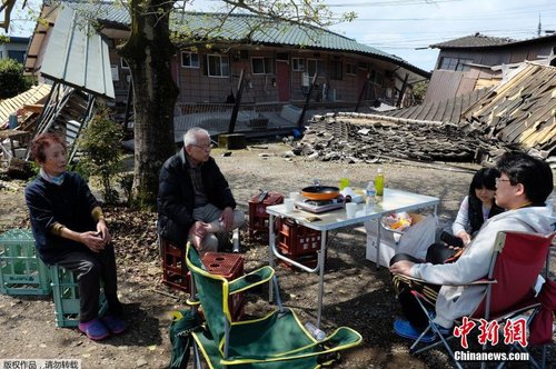 當地時間4月17日，日本熊本縣震后見聞。一家人圍坐在簡易桌旁吃飯，周圍都是倒塌的房屋。