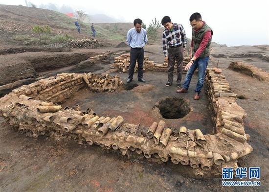 在桐木嶺礦冶遺址，考古人員查看用廢棄坩堝壘筑的房屋遺址（11月18日攝）。