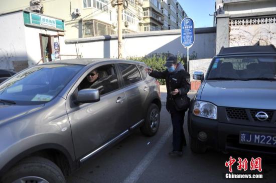 今年元月起，北京全市3000多名路側停車管理員上崗證更換，新上崗證標有二維碼，市民用手機掃描即可看到管理員的照片、姓名、所在公司、監督電話等詳細信息。若冒用或偽造，掃描出來的信息將與實際不符，一旦遇到假收費員，市民有權拒絕交費。圖為停車場管理員張大姐為車主指揮倒車。<a target='_blank' href='http://www.chinanews.com/' >中新網</a>記者 金碩 攝