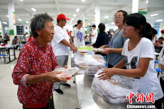 8月24日，志愿者在濰坊壽光市營(yíng)里鎮(zhèn)第二初級(jí)中學(xué)安置點(diǎn)為災(zāi)民發(fā)放救援物資。　梁犇 攝