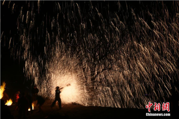 該村“打樹花”的習俗已延續了近600年，村民將生鐵融成鐵水后，再用特制的木板將鐵水擊打至樹上，頓時綻放出萬點“鐵花”。中新社記者 陳昊 攝